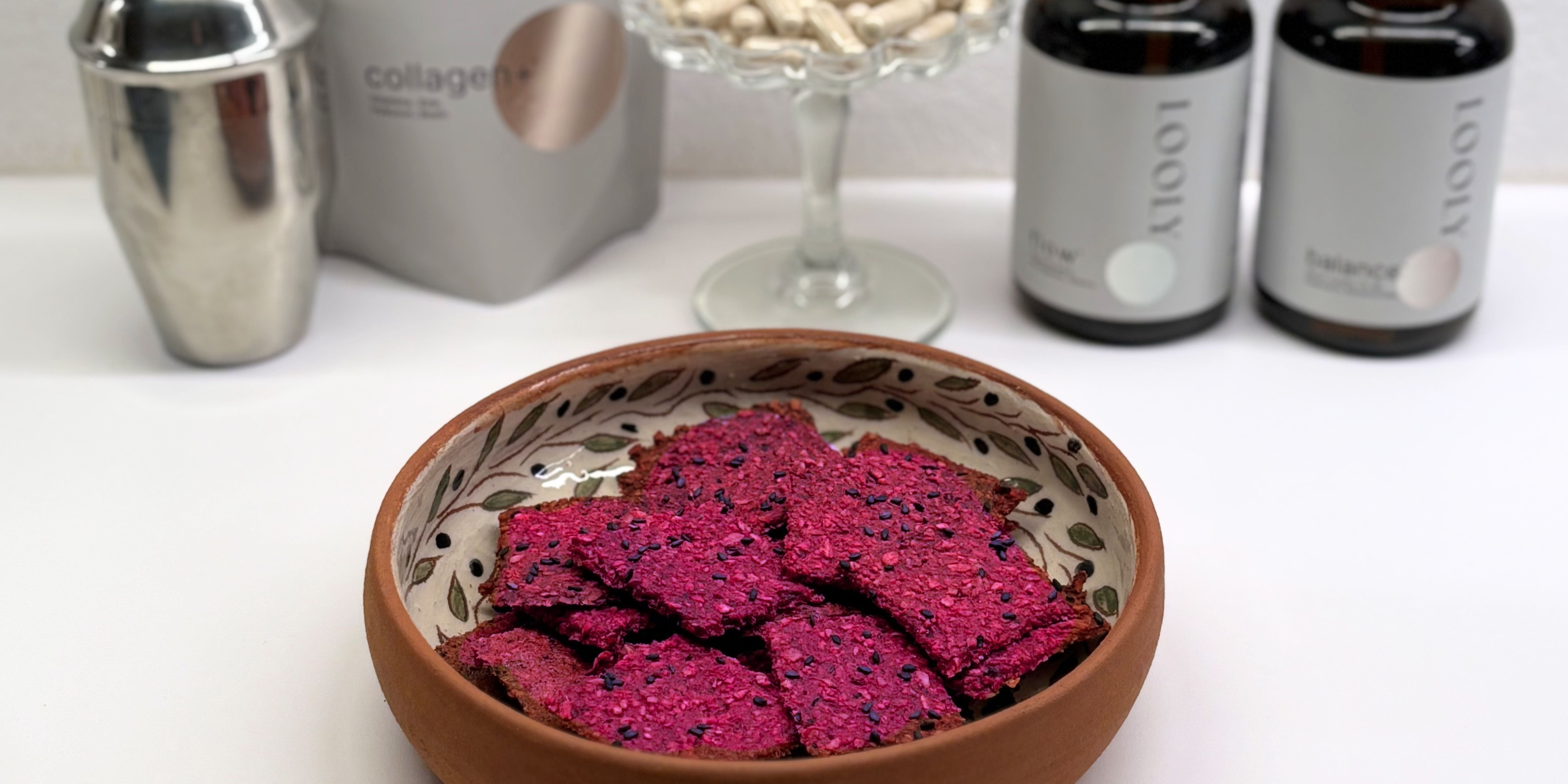 Rote-Beete-Cracker in einer Schale, mit LOOLY Produkten im Hintergrund