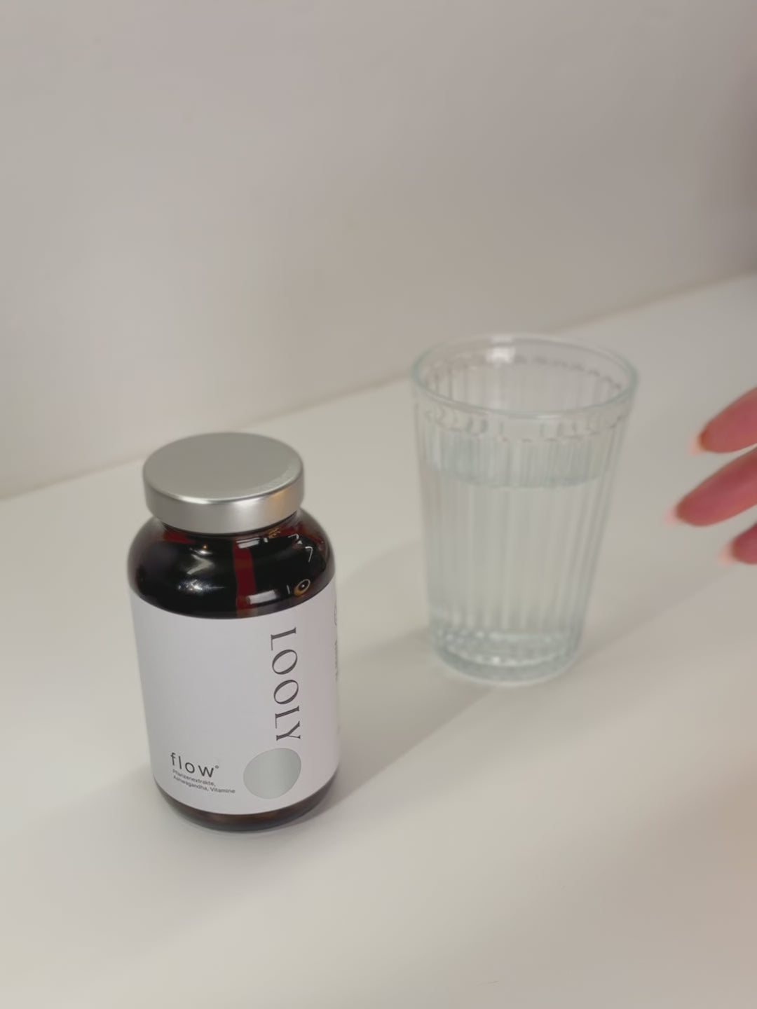 Video von Hand, die zwei Kapseln aus flow nimmt und ein Wasserglass greift 